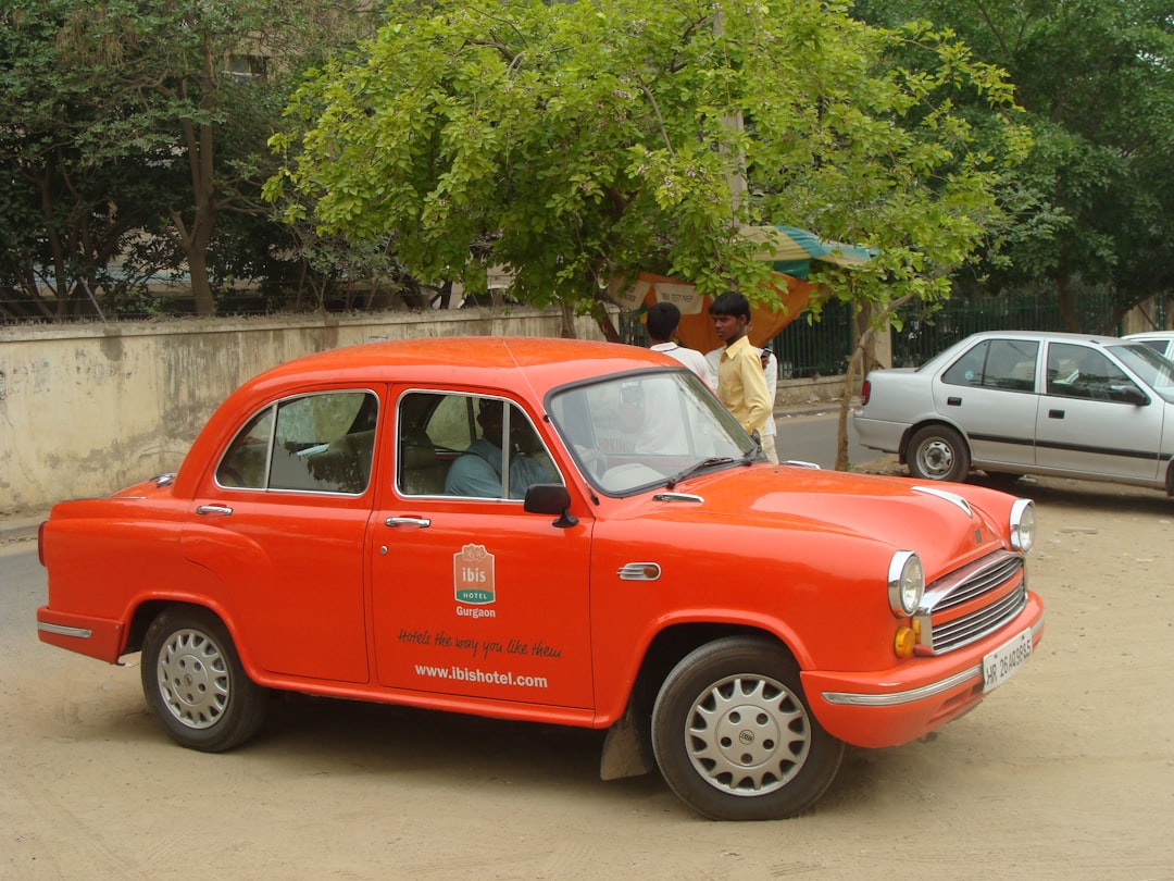 An orange hindustan ambassador car parked on a city street